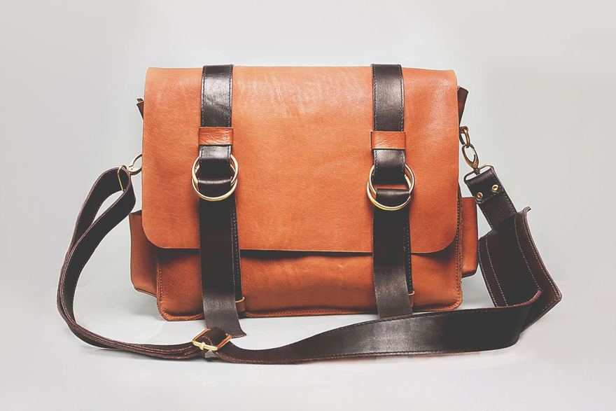 A leather messenger bag photographed against a plain gray studio backdrop